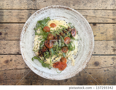 Healthy Breakfast: Scrambled eggs topped with avocado and arugula, accented with black sesame and spices 137293342