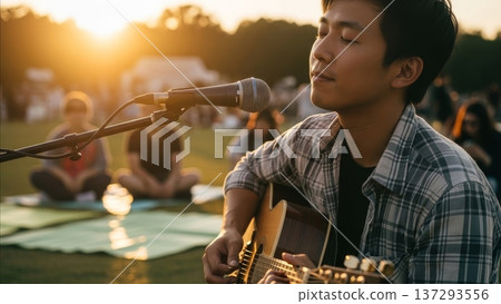 Asian male musician performing acoustic guitar and singing at outdoor music festival during golden hour sunset Asian male musician performing acoustic guitar and singing at outdoor music festival during golden hour sunset 137293556