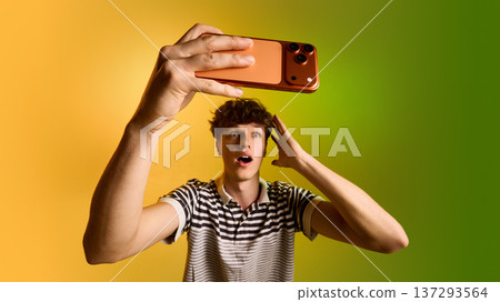 Young man taking selfie with smartphone on yellow green gradient background. 137293564