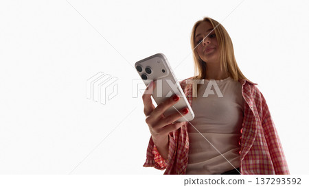Young woman using smartphone from low angle isolated on white background. Young woman using smartphone from low angle isolated on white background. 137293592
