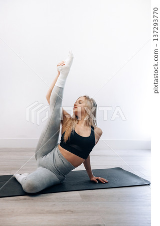 Young Female Practices Seated Side Stretch Exercise In Indoor Gym Space Focusing On Health. Girl Stretching, Enjoying Fitness Training Yoga And Healthy Lifestyle. 137293770