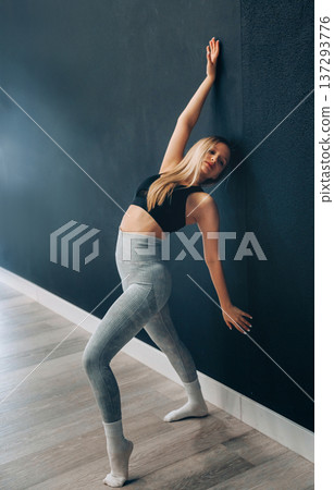 A Young Woman Is Performing A Stretching Exercise In Activewear, Positioning Her Body Against A Wall In A Gym. Girl Stretching, Enjoying Fitness Training A Young Woman Is Performing A Stretching Exercise In Activewear, Positioning Her Body Against A Wall In A Gym. Girl Stretching, Enjoying Fitness Training 137293776
