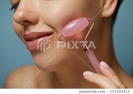 Face massage. Smiling Woman Using Jade Facial Roller for Skin Care, Beauty Treatment. Girl Using Natural Massager Closeup Portrait. 137293813