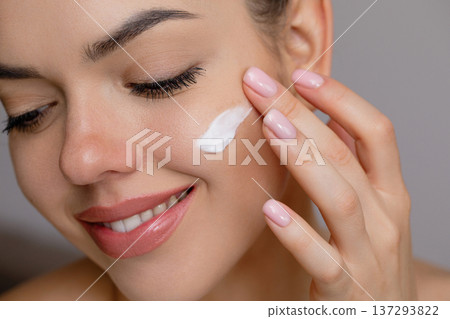 Skin care. Woman with beauty face touching healthy facial skin portrait. A beautiful girl model is applying a cream smear. Skin care. Woman with beauty face touching healthy facial skin portrait. A beautiful girl model is applying a cream smear. 137293822