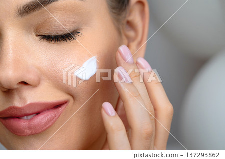 Skin care. Beauty close up portrait of young woman with a glowing skin is applying a skincare product. Hydration. Cream smear. Beautiful model with natural makeup touching her skin Skin care. Beauty close up portrait of young woman with a glowing skin is applying a skincare product. Hydration. Cream smear. Beautiful model with natural makeup touching her skin 137293862