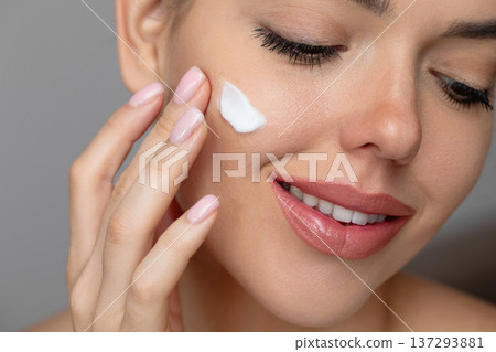 Beauty Woman face skin care. Beautiful close up portrait of a young woman with a glowing skin is applying a skincare product. Cream smear. Beauty Woman face skin care. Beautiful close up portrait of a young woman with a glowing skin is applying a skincare product. Cream smear. 137293881