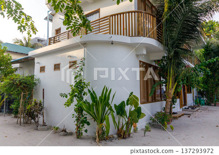 White villa with wooden balcony and tropical plants White villa with wooden balcony and tropical plants 137293972