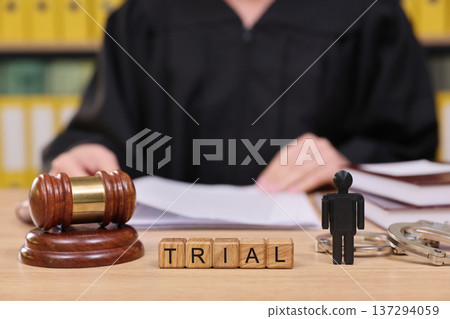 Courtroom scene highlights the tension of a trial as a judge prepares to make a ruling surrounded by legal symbols and documents Courtroom scene highlights the tension of a trial as a judge prepares to make a ruling surrounded by legal symbols and documents 137294059