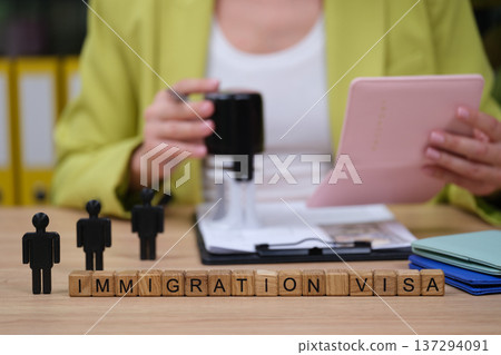 Preparing immigration documents while seated at a work desk with creative materials around 137294091