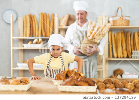 Baker dad and daughter are standing near product range in bakery kitchen. 137294159