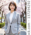 The woman herself is standing on a tree-lined street wearing a gray suit. 137294292