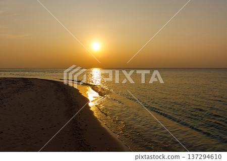 Golden sun sets over calm sea horizon Golden sun sets over calm sea horizon 137294610
