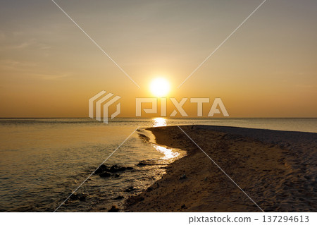 Golden sun dips low over calm ocean waters Golden sun dips low over calm ocean waters 137294613