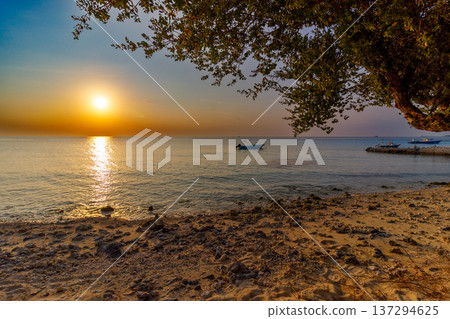 Golden sun dips low over calm ocean waters Golden sun dips low over calm ocean waters 137294625