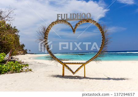 Golden heart frame stands on pristine white sand Golden heart frame stands on pristine white sand 137294657
