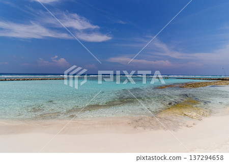 Crystal waters meet soft sand beneath a clear sky Crystal waters meet soft sand beneath a clear sky 137294658