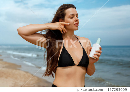 Attractive woman enjoying sun at beach with sunscreen lotion, summer skincare and sun protection concept with relaxed lifestyle and glowing skin Attractive woman enjoying sun at beach with sunscreen lotion, summer skincare and sun protection concept with relaxed lifestyle and glowing skin 137295009