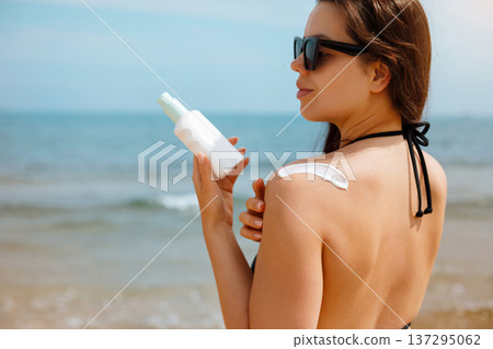 Woman Holding Suncream Sunscreen Lotion Bottle at Sunny Beach Woman Holding Suncream Sunscreen Lotion Bottle at Sunny Beach 137295062