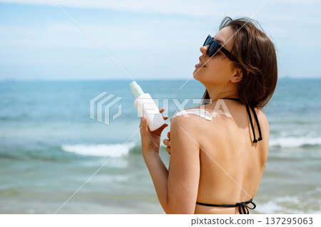Woman Using Suncream Sunscreen Lotion in Sunglasses at Beach Woman Using Suncream Sunscreen Lotion in Sunglasses at Beach 137295063