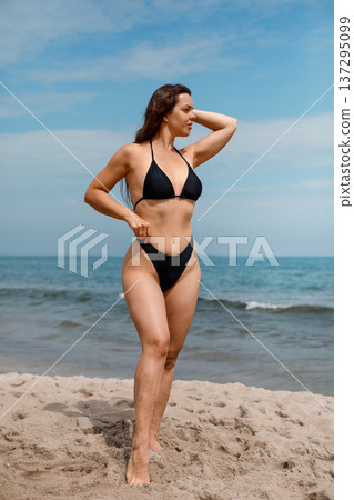 Attractive woman posing on beach touching hair enjoying sunlight and applying sunscreen suncream lotion for UV protection skincare and summer wellness lifestyle Attractive woman posing on beach touching hair enjoying sunlight and applying sunscreen suncream lotion for UV protection skincare and summer wellness lifestyle 137295099