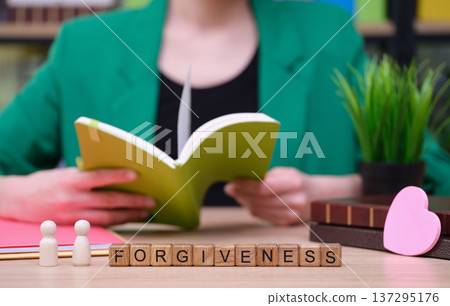 Exploring the concept of forgiveness through reading in a cozy, serene workspace surrounded by greenery and colorful books Exploring the concept of forgiveness through reading in a cozy, serene workspace surrounded by greenery and colorful books 137295176