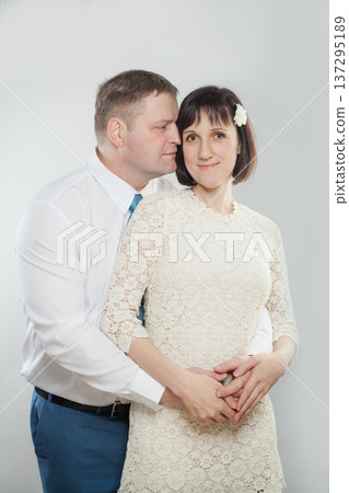 A couple poses together in a studio setting. They smile and display affection for each other. A couple poses together in a studio setting. They smile and display affection for each other. 137295189