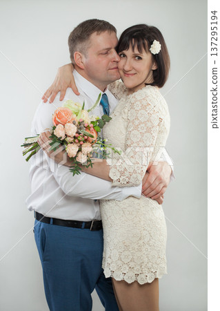 Couple celebrates their wedding day with a warm embrace and a bouquet of flowers 137295194