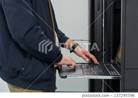IT technician configuring a rack server using a slide-out console laptop in a data center IT technician configuring a rack server using a slide-out console laptop in a data center 137295596