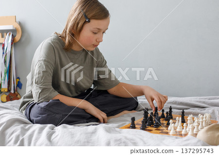 Cute child boy playing chess board game indoor. Kid 11 years old with chess at home Cute child boy playing chess board game indoor. Kid 11 years old with chess at home 137295743