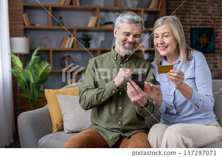 Senior couple finding pleasure and convenience using a smartphone and credit card for online shopping at home, performing digital payment transactions together with modern financial technology Senior couple finding pleasure and convenience using a smartphone and credit card for online shopping at home, performing digital payment transactions together with modern financial technology 137297071
