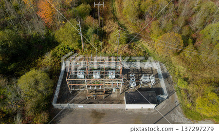 Aerial view of electrical substation with power transformers and transmission lines in forest landscape Aerial view of electrical substation with power transformers and transmission lines in forest landscape 137297279