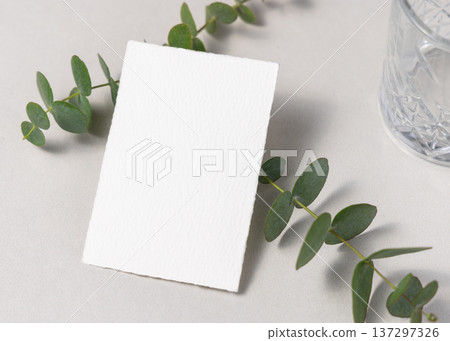 Mockup of blank card near green eucalyptus branche sand crystal glasses. Presentation template Mockup of blank card near green eucalyptus branche sand crystal glasses. Presentation template 137297326