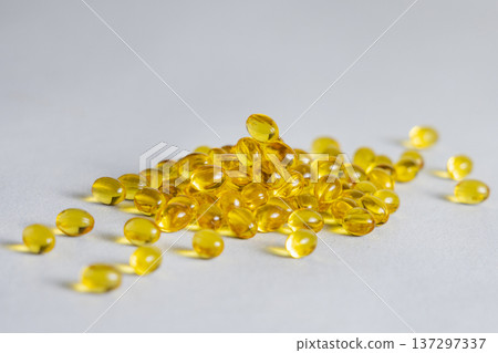 Yellow softgel scattered from transparent jar on greige ston, Nutritional supplements or vitamins 137297337