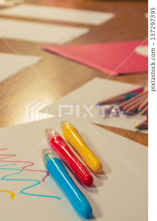 Three colorful red, blue and yellow crayons on white paper with playful scribbles, 137297395