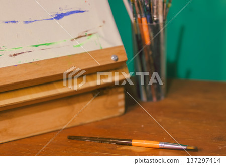 an orange paintbrush, arranged on a warm wooden table in an artist's studio, symbolizing creativity an orange paintbrush, arranged on a warm wooden table in an artist's studio, symbolizing creativity 137297414