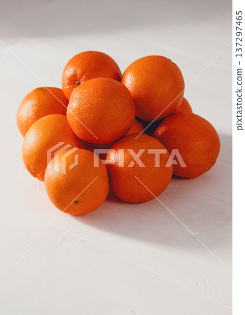 Bright oranges piled on white surface. Smooth texture with natural dimples. Clean background enhances vibrant color 137297465