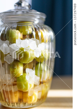 A storage jar for homemade plum syrup made with green plums and rock sugar A storage jar for homemade plum syrup made with green plums and rock sugar 137297489