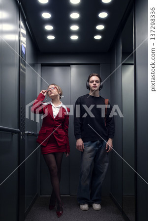 Businesswoman and young man standing together in office elevator in modern building interior. Businesswoman and young man standing together in office elevator in modern building interior. 137298336
