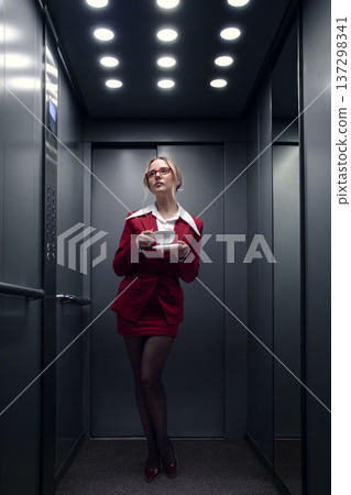 Elegant businesswoman drinking coffee in elevator during morning commute. 137298341