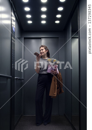Young woman recording voice message on smartphone while holding bouquet. Young woman recording voice message on smartphone while holding bouquet. 137298345