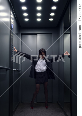 Businesswoman stretching arms inside elevator during office break. 137298352