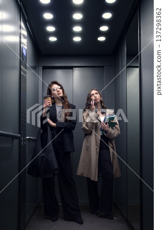Two professional women waiting in elevator during office workday Two professional women waiting in elevator during office workday 137298362