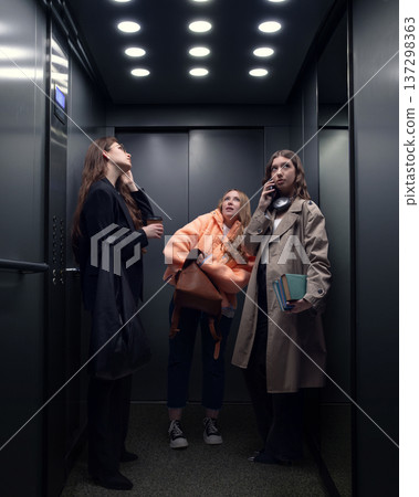 Three young women using elevator during busy city workday. Three young women using elevator during busy city workday. 137298363