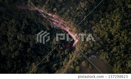 Cassilandia, Mato Grosso do Sul, Brazil - 04 05 2024. Drone aerial view of Cachoeira do Socorro waterfall flowing over a rocky cliff surrounded by dense forest vegetation during early morning light. Cassilandia, Mato Grosso do Sul, Brazil - 04 05 2024. Drone aerial view of Cachoeira do Socorro waterfall flowing over a rocky cliff surrounded by dense forest vegetation during early morning light. 137298623