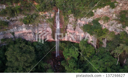Cassilandia, Mato Grosso do Sul, Brazil - 04 05 2024. Drone aerial view of Cachoeira do Socorro waterfall flowing over a rocky cliff surrounded by dense forest vegetation during early morning light. Cassilandia, Mato Grosso do Sul, Brazil - 04 05 2024. Drone aerial view of Cachoeira do Socorro waterfall flowing over a rocky cliff surrounded by dense forest vegetation during early morning light. 137298627