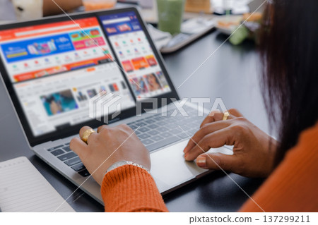 Close up of an Asian woman hand using laptop computer for online shopping and browsing e-commerce website at cafe. Concept of digital marketing, retail business, and modern consumer lifestyle. Close up of an Asian woman hand using laptop computer for online shopping and browsing e-commerce website at cafe. Concept of digital marketing, retail business, and modern consumer lifestyle. 137299211