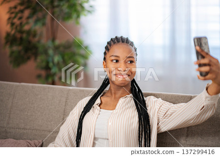 Young woman taking selfie with smartphone on sofa Young woman taking selfie with smartphone on sofa 137299416