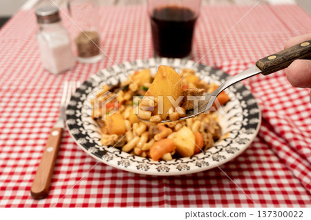 Eating beef stew with noodles and vegetables Eating beef stew with noodles and vegetables 137300022