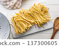 Fresh pasta ready for cooking, showing strands of fettuccine and bigoli set on white table. 137300605