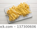 Fresh pasta ready for cooking, showing strands of fettuccine and bigoli set on white table. 137300606